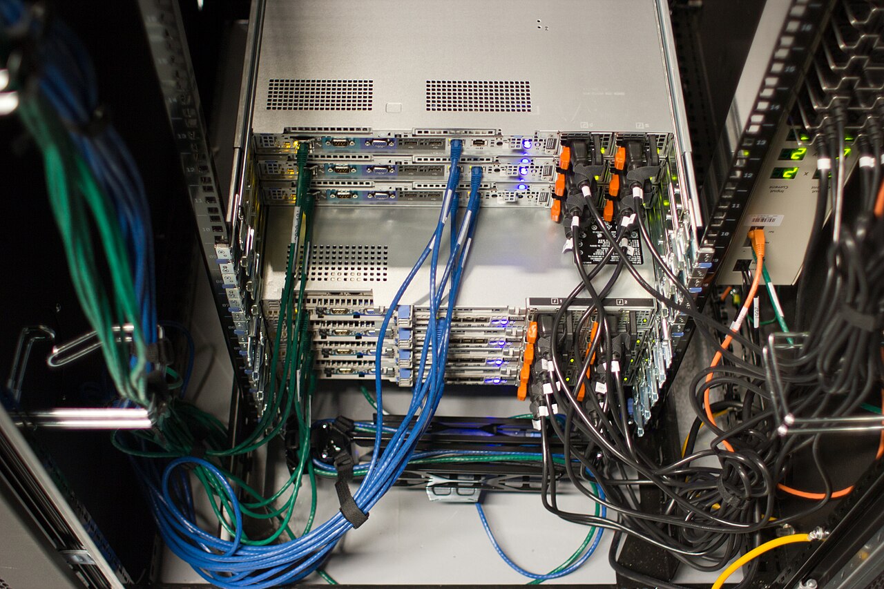 Archive photograph of the rear of Wikimedia Foundation server equipment with dense blue and black network cabling.