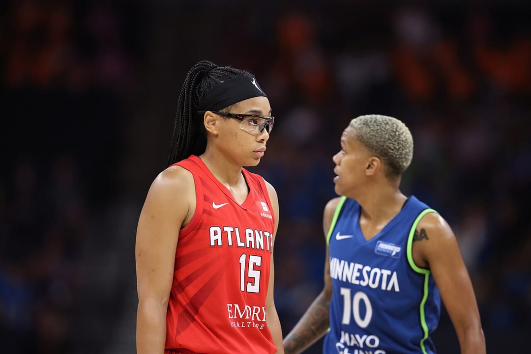 Allisha Gray in a red Atlanta number 15 uniform beside a Minnesota player during a July 2024 game.